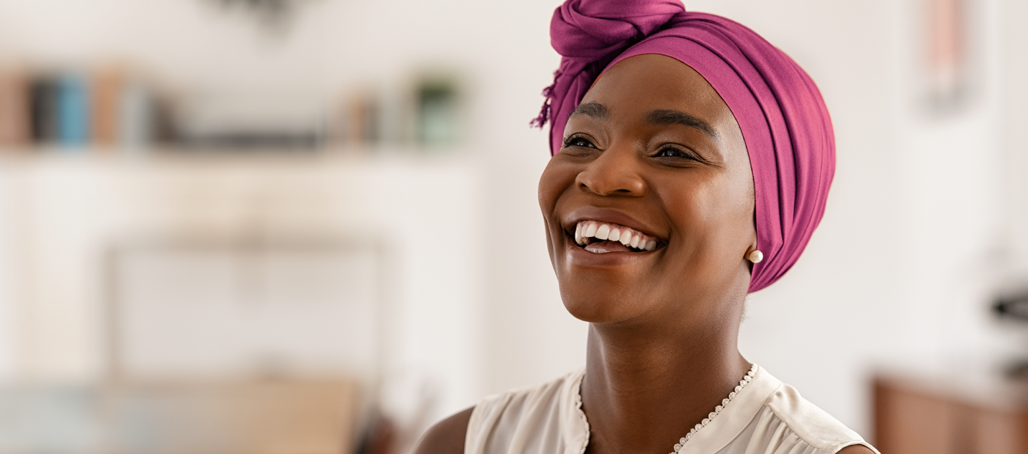 Foto do rosto de uma mulher negra sorrindo. Ela tem idade por volta de 35 anos, usa um turbante de cor fúcsia e uma blusa branca sem mangas. Do lado esquerdo da foto, há o texto “Planos Odonto Empresas. Feitos pra você sorrir. A partir de R$ 39,90 por mês.